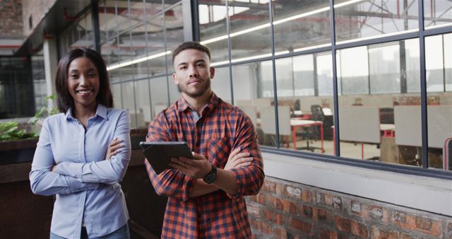 Two professionals standing confidently in a modern coworking space. Ideal for business, teamwork, collaboration, or office culture themes. They can be used in contexts promoting diversity, business environments, career development, or professional teamwork.