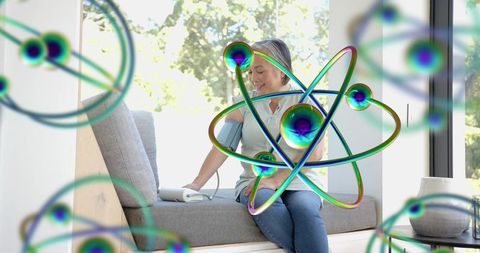 Asian woman checking blood pressure at window seat with modern home wellness atom overlay