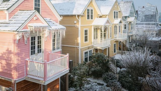 Pastel houses lining snowy street featuring icicles, porches, dormers and balconies