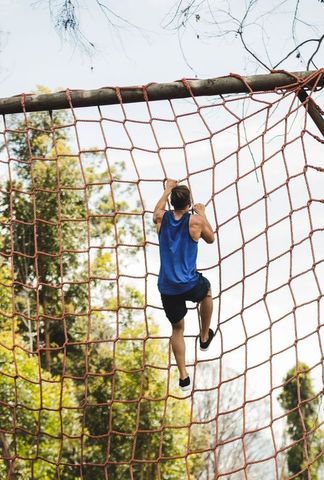 Man Climbing Rope Net on Outdoor Forest Obstacle Course