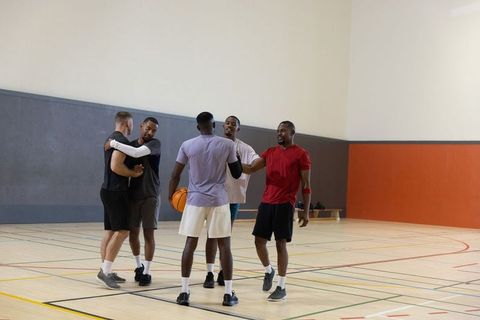 Multiracial teammates bumping fists and celebrating on indoor basketball court