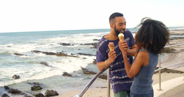 Romantic diverse couple standing by railing and eating ice creams, copy space. Summer, vacation, romance, love, relationship, free time and lifestyle, unaltered.