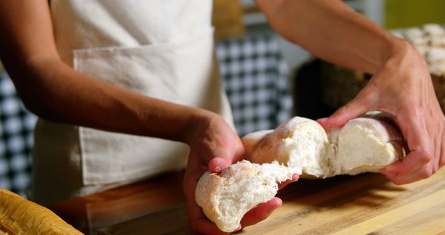 Baker Splitting Freshly Baked Bread in Kitchen - Download Free Stock Images Pikwizard.com