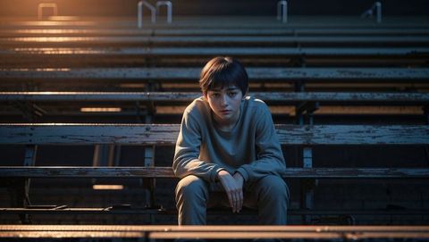 Teen sits in contemplative solitude on urban bleachers - shy concept