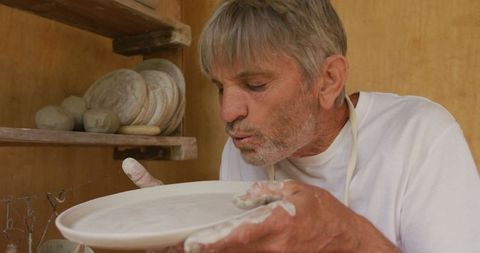 Senior Man in Pottery Studio Examining Ceramic Dish