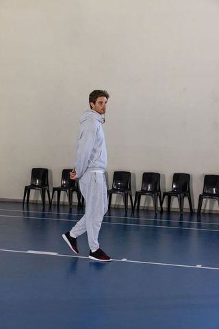 Young man walking in gym wearing grey tracksuit, modern fitness theme