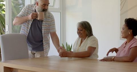 Senior Man Serving Coffee to Family in Bright Modern Living Room