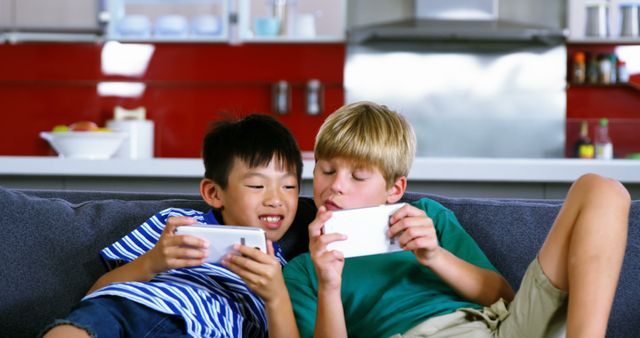 Two Children Playing Mobile Games on Sofa in Modern Kitchen - Download Free Stock Images Pikwizard.com