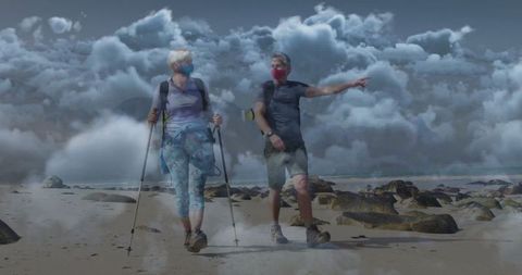 Couple Trekking along Rocky Shore under Cloudy Sky
