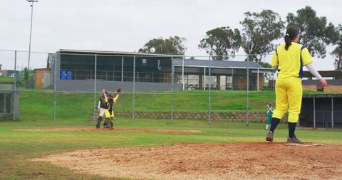 Female softball pitcher throws ball on sports field