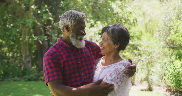 Senior couple embracing with smiles in a lush garden, radiating happiness and love. Ideal for themes of aging gracefully, relationships, affection, and retirement. Can be used in brochures, articles, or ads focusing on senior lifestyle, wellness, and family values.