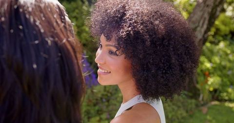 Joyful woman with curly hair enjoying garden conversation
