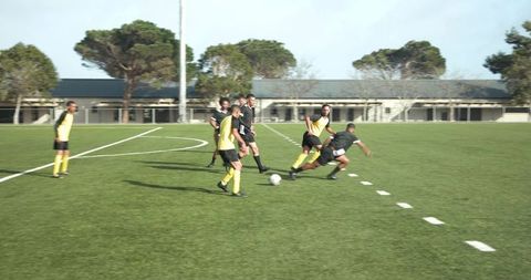 Youth soccer match on sunlit field near school