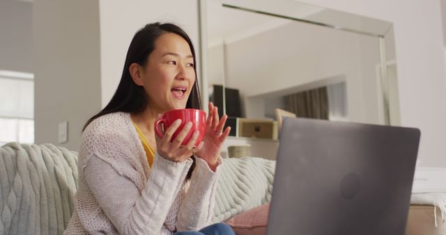 Image of happy asian woman wit coffee using laptop. Leisure, relax, spending time at home with technology concept.
