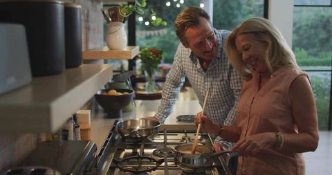 Laughing Senior Couple Cooking Together in Contemporary Kitchen