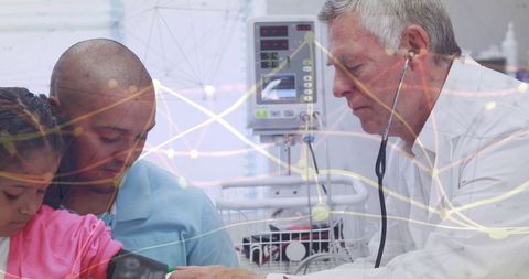 Senior doctor using stethoscope on child's arm in hospital room