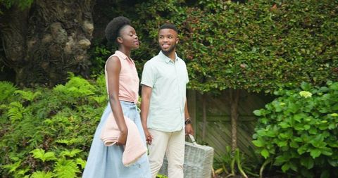 Happy Couple Walking with Picnic Basket in Green Park Setting