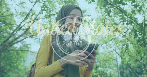 Smiling woman in headscarf using smartphone outdoors