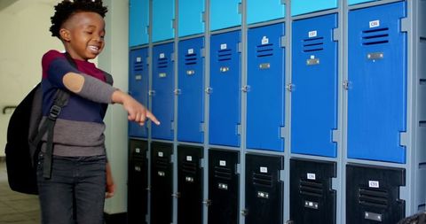 Smiling boy pointing at colorful school lockers