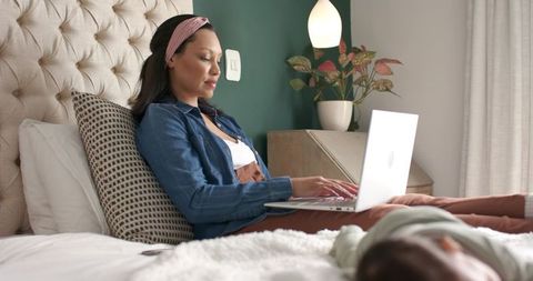 Mother Balancing Work and Baby in Cozy Bedroom Setting