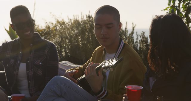 Friends Enjoying Outdoor Sunset, Playing Guitar and Laughing Together - Download Free Stock Images Pikwizard.com