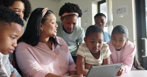 African American teacher guiding students with tablet for interactive classroom learning