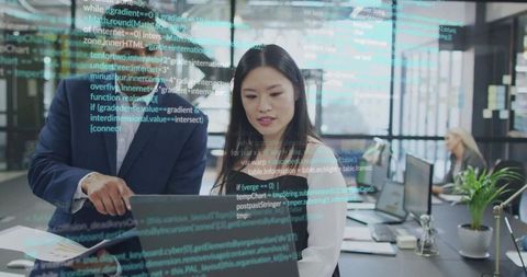 Business professionals collaborating on laptop with code overlay in modern open-plan office