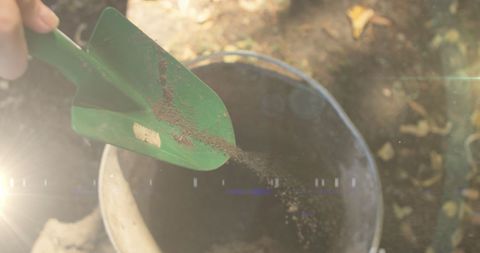 Hands Scatting Soil Intro Bucket with Garden Spade