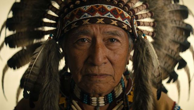 Indigenous elder wearing feathered headdress close-up portrait with beadwork