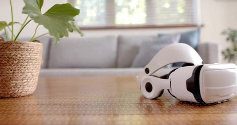 Resting white VR headset on wooden table in bright living room with woven basket