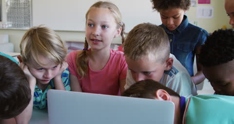 Engaged Schoolchildren Collaborating on Laptop Computer