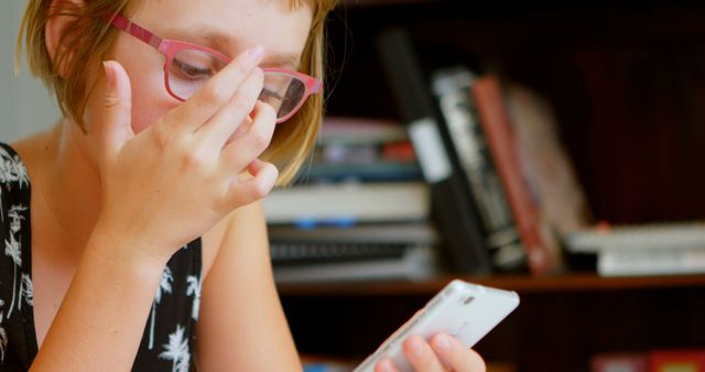 Woman wearing glasses reacting with surprise while looking at smartphone - Download Free Stock Images Pikwizard.com