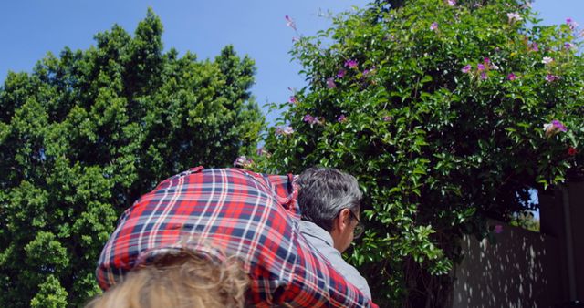 Father Giving Child Piggyback Ride in Vibrant Garden - Download Free Stock Images Pikwizard.com