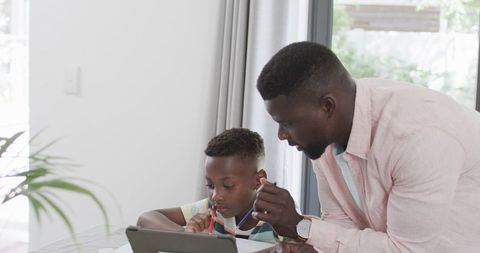 Father Assisting Son with Homework on Tablet