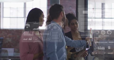 Multicultural team collaborating at glass wall with interactive dashboards and analytics