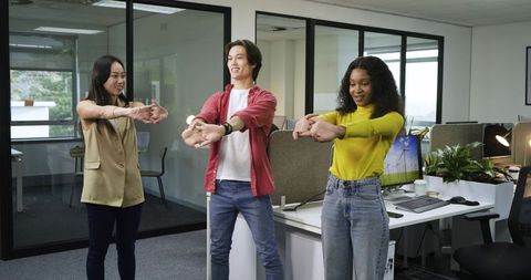 Diverse team stretching wrist in modern office for ergonomic wellness