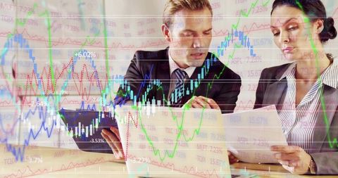Business professionals analyzing financial charts and documents during boardroom meeting