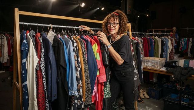Fashion stylist organizing colorful wardrobe rack in warehouse
