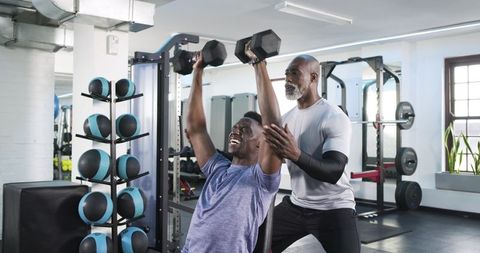 Personal Trainer Assisting Client During Incline Dumbbell Press Workout