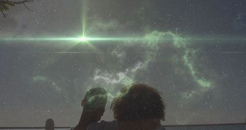 Couple enjoying stargazing under shimmering green nebula