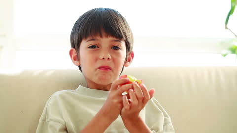 Smiling Child Enjoying Red Apple at Home