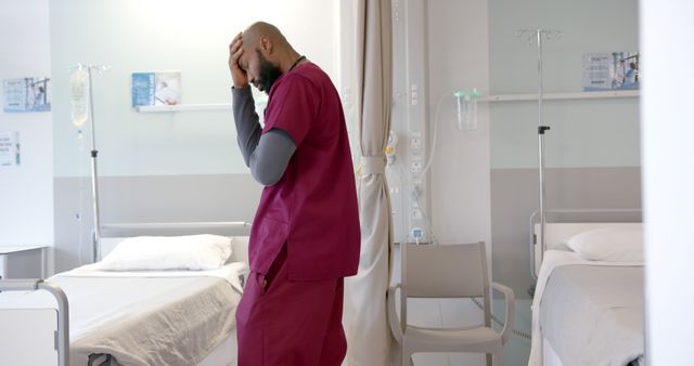Depiction of a stressed healthcare worker wearing scrubs in a hospital ward. Suitable for articles, blog posts, or campaigns addressing healthcare professional burnout, stress in medical environments, or the challenges faced by healthcare workers.