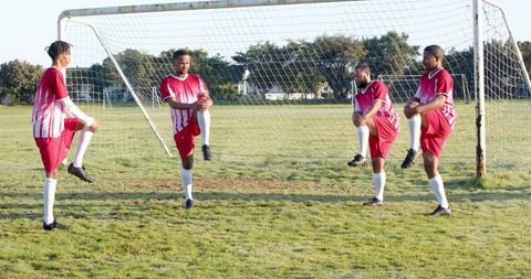 Teammates Stretching on Soccer Pitch Before Match