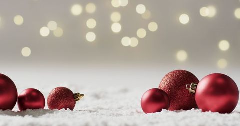 Red Christmas Ornaments on Snow with Bokeh Holiday Background