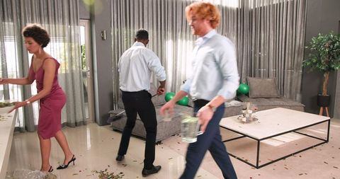 Friends tidying after celebration in modern living room