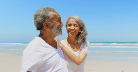 Joyful Senior Couple Walking on Sunny Beach Smiling