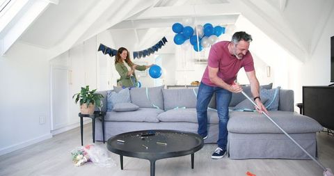 Couple Cleaning After Birthday Party at Home with Balloons