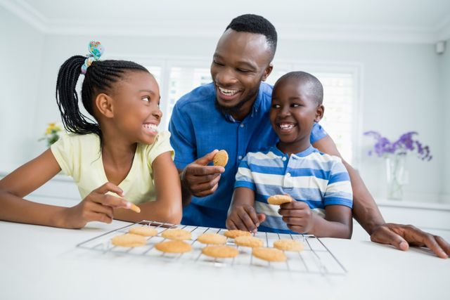 Smiling father and kids interacting while eating cookies at home