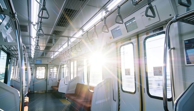Empty commuter carriage bathing in golden sunlight with brown seats and steel handrails