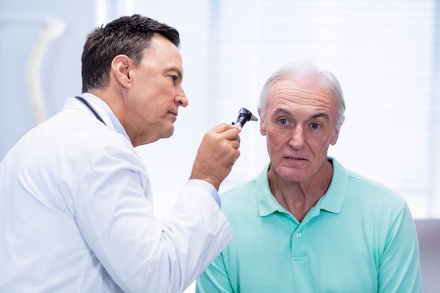 Doctor using otoscope to examine senior patient's ear in a clinical setting. Useful for healthcare, medical checkups, elderly care, and professional medical services. Ideal for illustrating medical consultations, patient care, and health diagnostics.